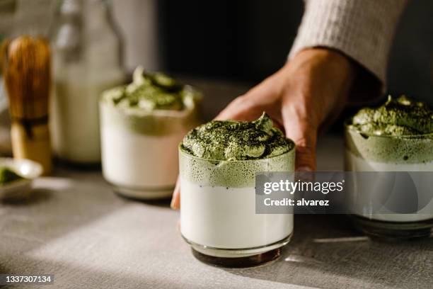 close-up of a female hand placing dalgona matcha latte glasses - dalgona 個照片及圖片檔