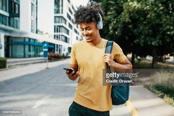 hombre millennial de raza mixta en el centro de la ciudad, usando teléfono móvil - mochila bolsa fotografías e imágenes de stock