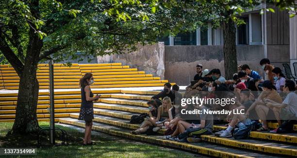 Class is being conducted by a instructor wearing a face mask, on the steps outside the classroom on the campus at State University of New York at...