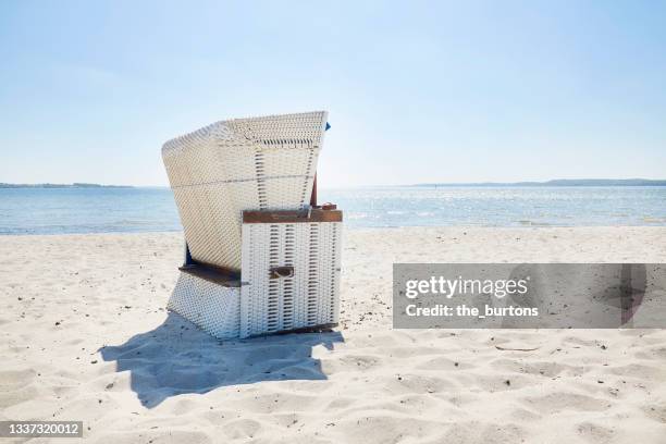 wicker beach chair at beach against blue sky - strandkorb stock-fotos und bilder