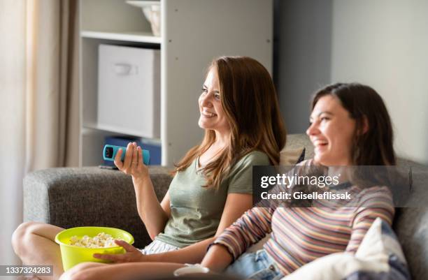 dos jóvenes amigas riendo mientras ven una película en casa - reality tv fotografías e imágenes de stock
