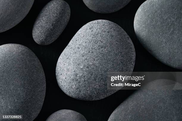 gray pebbles on black close up view - steen stockfoto's en -beelden