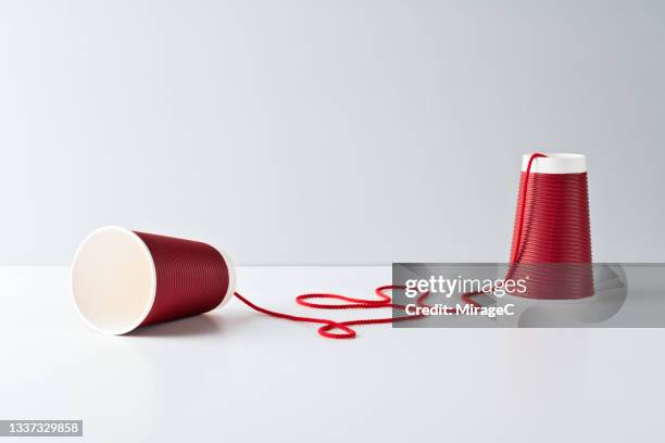 red paper cup string telephone - red string connections stock pictures, royalty-free photos & images