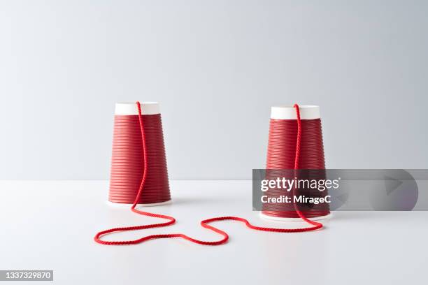 red paper cup string telephone - red string connections stock pictures, royalty-free photos & images
