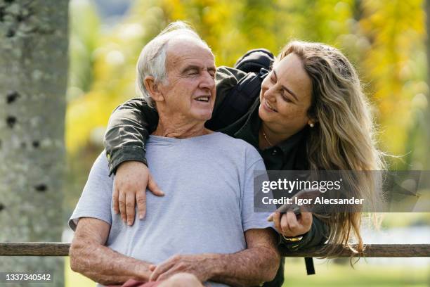 daughter hugging father on park bench - blind man stockfoto's en -beelden