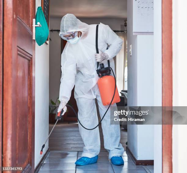 foto de un hombre con un traje de materiales peligrosos usando un pulverizador químico para desinfectar una casa - crime scene cleaners fotografías e imágenes de stock