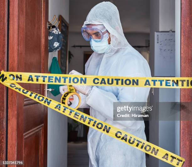 foto de un trabajador con un traje protector acordonando un área con cinta de barrera - hazmat fotografías e imágenes de stock