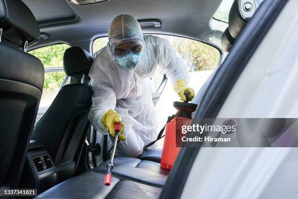 shot of a man in a hazmat suit using a chemical sprayer to sanitise a car - clean car interior stock pictures, royalty-free photos & images