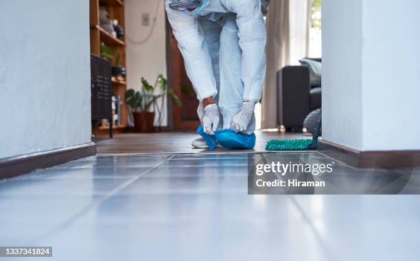primer plano de un hombre irreconocible con un traje de materiales peligrosos que se pone protectores de zapatos azules en una casa - mono blanco traje protector fotografías e imágenes de stock