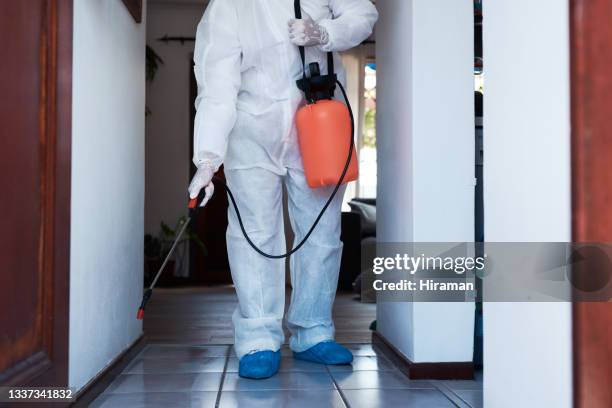 primer plano de un limpiador irreconocible en un traje de materiales peligrosos usando un pulverizador químico para desinfectar una casa - crime scene cleaners fotografías e imágenes de stock