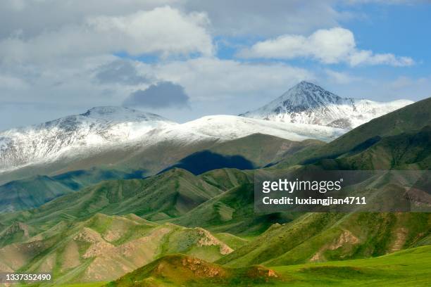 majestätische schneebedeckte berge und hügelige prärie in bayanbulak - plateau stock-fotos und bilder
