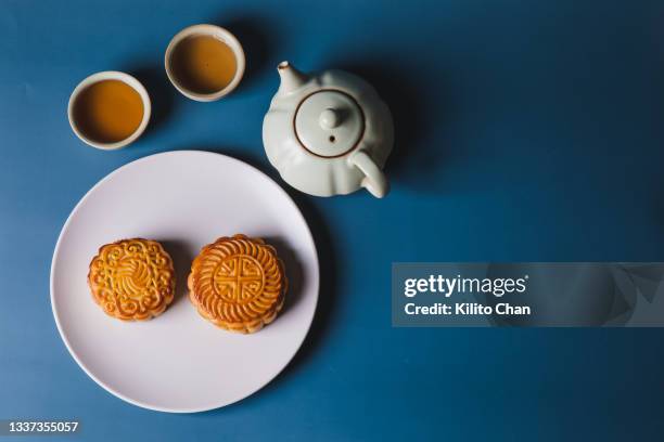 overhead view of traditional cantonese style mooncakes on a plate and tea set against blue background - cup of tea from above stock pictures, royalty-free photos & images