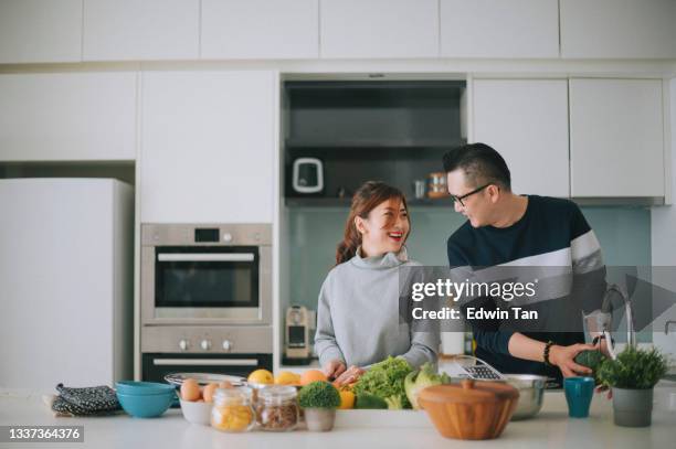 asian chinese married couple preparing food together in the kitchen counter and having bonding time during weekend - couples showering 個照片及圖片檔