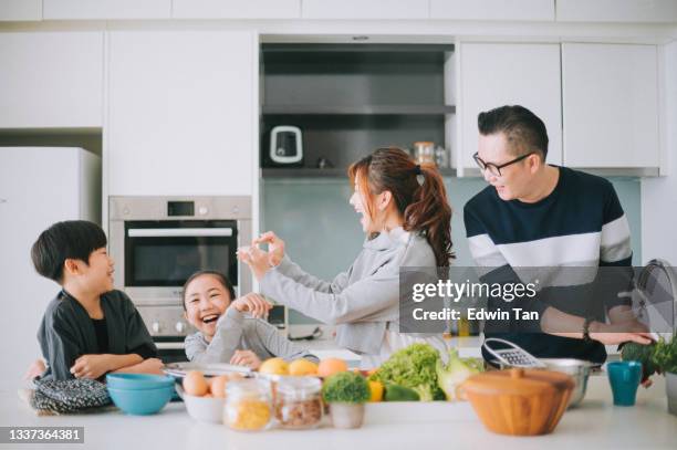 juguetón asiático chino joven familia con 2 niños preparando comida en la cocina disfrutando de un tiempo divertido juntos - familia en casa fotografías e imágenes de stock