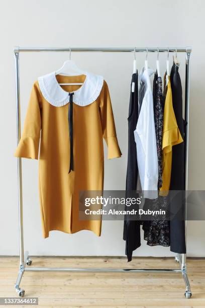 modern fashion designer clothes hanging on the rail - multi colored dress photos et images de collection