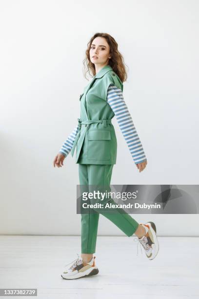 woman model in green stylish suit posing making a step and looking at the camera - portrait of young woman standing against steps stockfoto's en -beelden