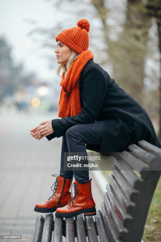 Jovem sentada no banco no inverno na cidade