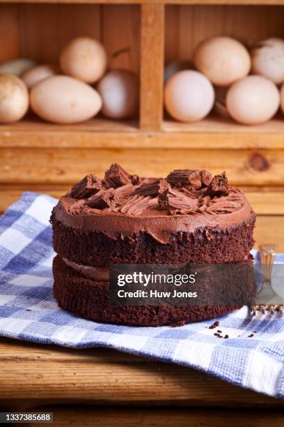 iced chocolate sponge cake shot on a wooden board in a home kitchen setting - chocolate cake 個照片及圖片檔