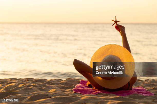 young woman sunbathing on the beach - brunbränd bildbanksfoton och bilder