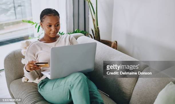 tiro de uma jovem usando seu cartão e laptop para fazer compras online em casa - zoom - fotografias e filmes do acervo