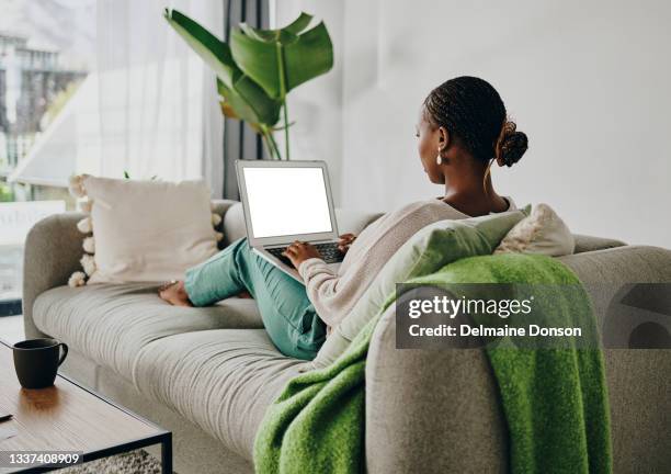 shot of a young woman working on her laptop on the couch at home - blogger woman stock pictures, royalty-free photos & images