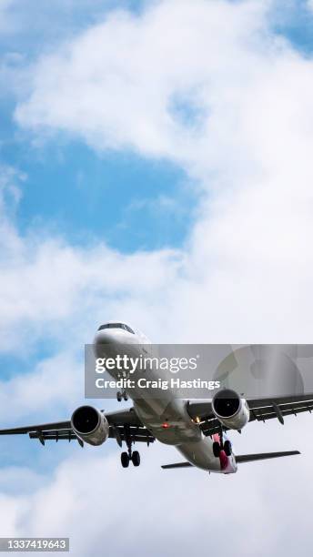 vertical close up tracking shot of plane coming into land with blue cloudy sky background - plane landing stock-fotos und bilder