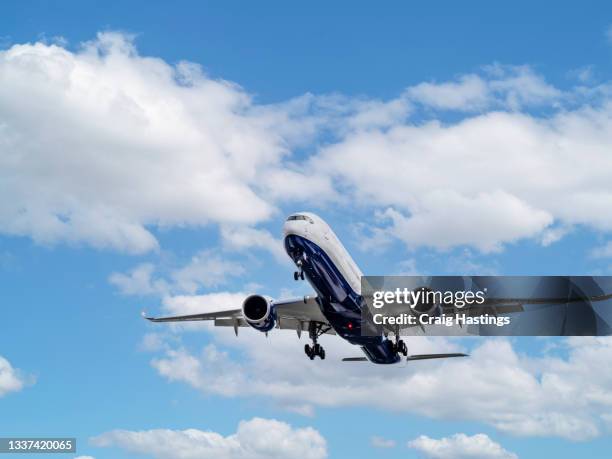 close up tracking shot of plane coming into land with blue cloudscape behind - plane stockfoto's en -beelden