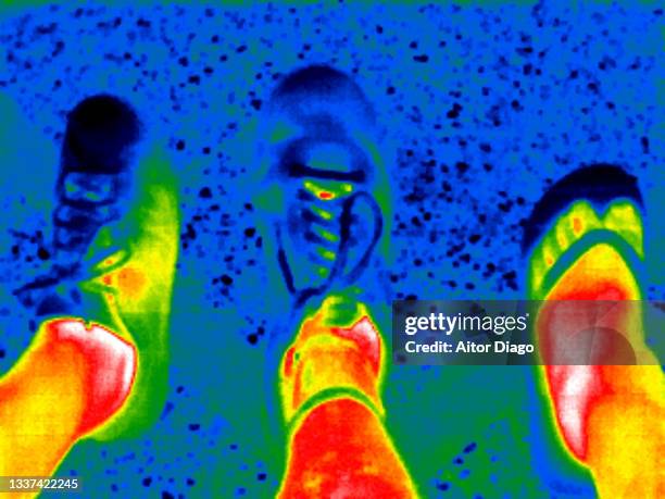 thermal image of the feet of a person with shoes and another wearing flip-flops. - red flip flops isolated stock pictures, royalty-free photos & images