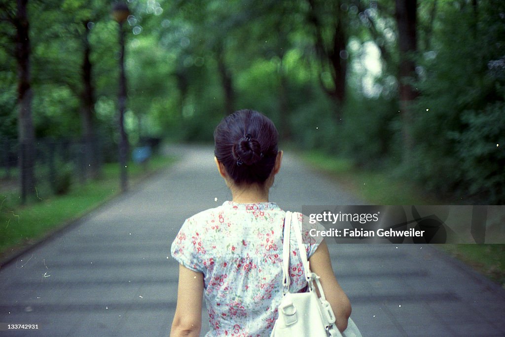 Rear view of woman with bag walking on road