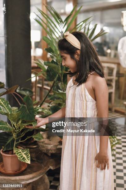 girl smiling and looking at potted plant in the porch - hair band stock pictures, royalty-free photos & images