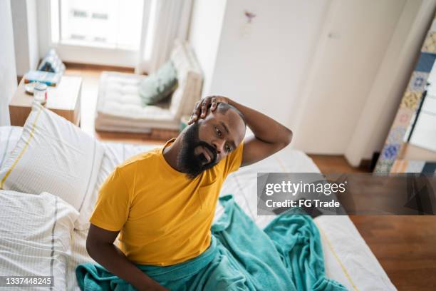 man waking up and stretching in bed at home - neck stretch stock pictures, royalty-free photos & images