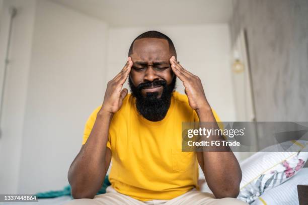 man waking up with headache at home - hangover headache stock pictures, royalty-free photos & images