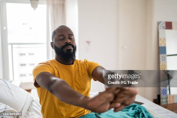 man waking up and stretching in bed at home - sleep routine stock pictures, royalty-free photos & images