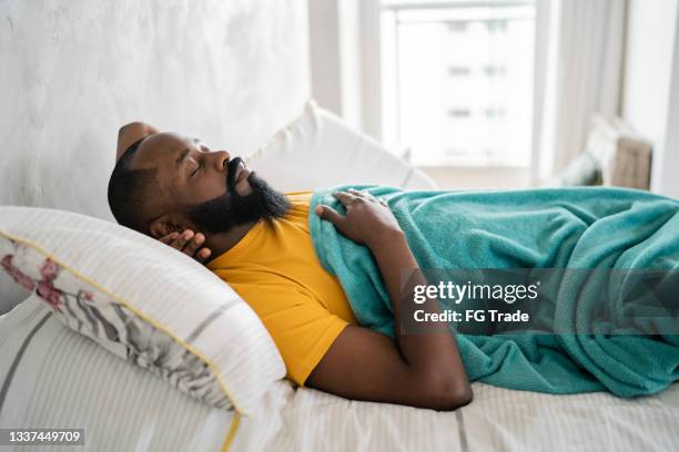 man sleeping on the bed at home - black man sleeping in bed stock pictures, royalty-free photos & images