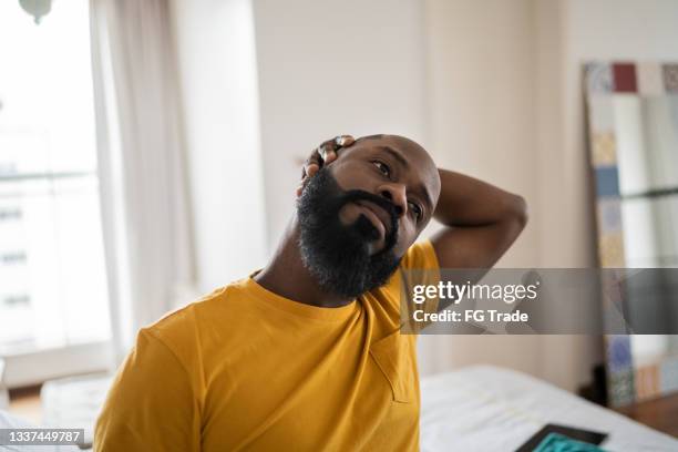 homem acordando e se esticando na cama em casa - black man sleeping in bed - fotografias e filmes do acervo