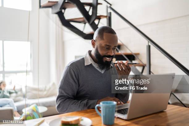 man using laptop and sending audio message on smartphone at home - voice search stock pictures, royalty-free photos & images