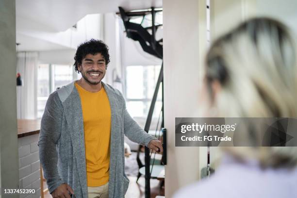 man opening door to guest at home - greeting guests stock pictures, royalty-free photos & images