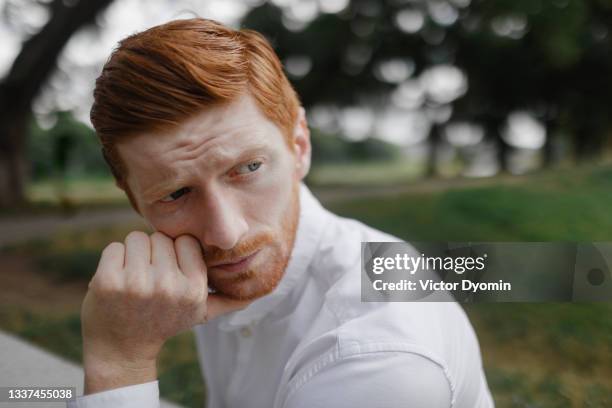 portrait of the thoughtful redhead man in the white shirt - suspicion 個照片及圖片檔