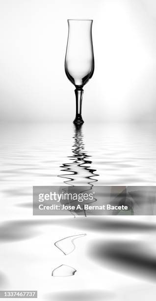 empty glass of champagne reflected on a water surface on a white background. - glass half full party stock pictures, royalty-free photos & images
