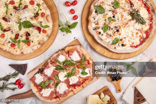 top view of different italian pizza on wooden board on white rustic background - parmesan cheese pizza stock pictures, royalty-free photos & images