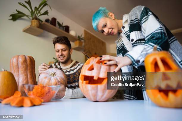 one happy young couple preparing pumpkins for halloween - carve out stock pictures, royalty-free photos & images