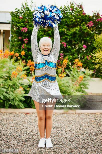 Wide shot portrait of smiling senior female cheerleader in backyard garden