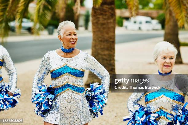 medium shot of smiling senior female cheerleaders practicing on summer morning - silver dress photos et images de collection