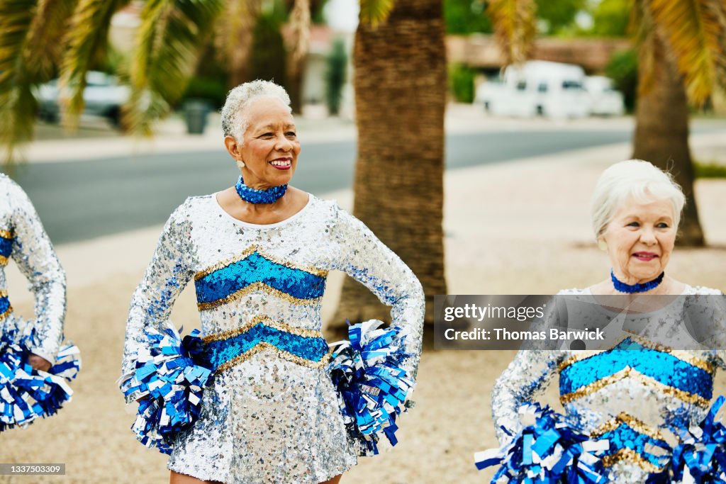 Medium shot of smiling senior female cheerleaders practicing on summer morning