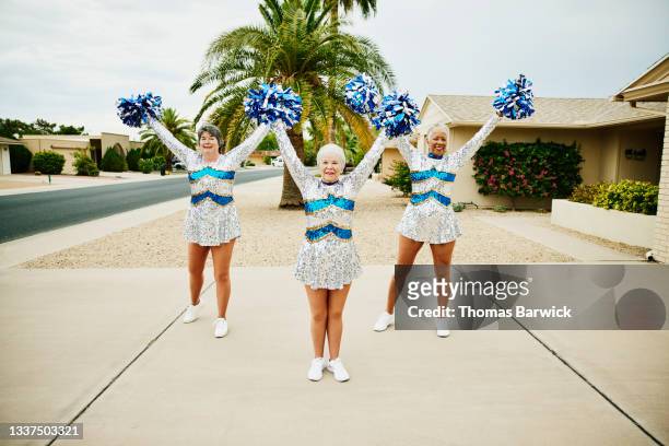 Wide shot of senior female cheerleaders practicing in driveway on summer morning