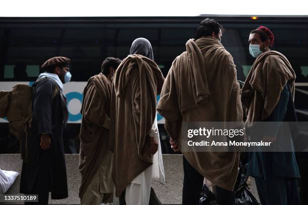 Refugees board a bus at Dulles International Airport that will take them to a refugee processing center after being evacuated from Kabul following...