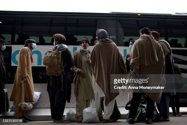 Refugees board a bus at Dulles International Airport that will take them to a refugee processing center after being evacuated from Kabul following...