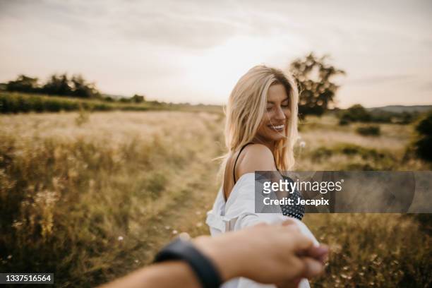 young woman standing in nature and holding her boyfriend's hand, follow me concept - follow me stock pictures, royalty-free photos & images