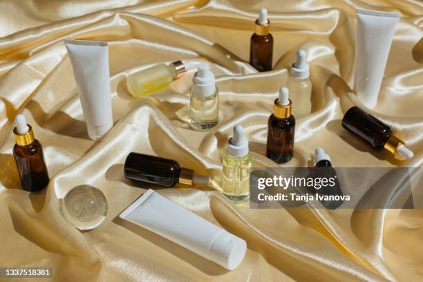 glass bottles for cosmetics with pipette, natural skincare and essential oil, moisturizer tubes on silk fabric beige background. beauty products. skin care concept. - cbd products stock pictures, royalty-free photos & images