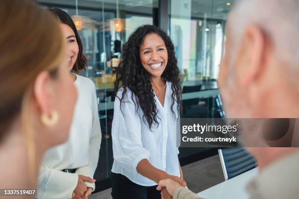 grupo de empresarios saludándose entre sí dándose la mano en una oficina. - experiencia cliente fotografías e imágenes de stock